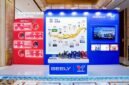 A display booth featuring Valvoline GEELY collaboration, showcasing co-developed lubricants and a timeline of their partnership, with product bottles arranged on a central table.