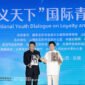 Li Zijun (right), a scholar of the Chinese Theatre Literature Society, displays a photo of his grandfather, Li Hongchun, portraying the legendary Chinese figure Guan Gong during the International Youth Dialogue on Loyalty and Honor Without Borders in Yuncheng, Shanxi province, on Wednesday. [Photo by Zhu Xingxin/China Daily]